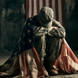 Veteran sitting with an American flag representing US Family Health Plan coverage for residential addiction treatment available at Sober First Recovery.