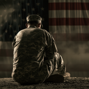 Veteran sitting in front of an American flag representing drug and alcohol rehab available at Sober First Recovery through US Family Health Plan.